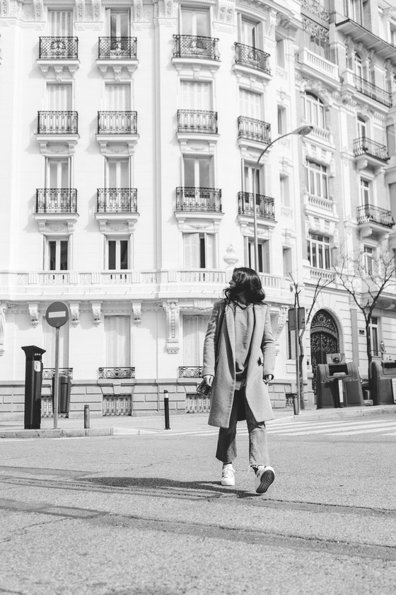 man in black coat walking on sidewalk in grayscale photography